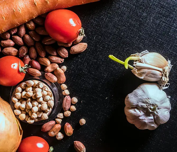 Garlic, tomatoes, and nuts arranged on dark surface for Garlic Shop lifestyle imagery